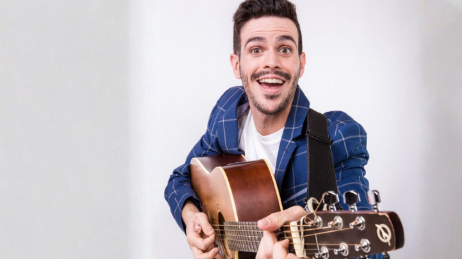 Lorenzo Baglioni, attore, ex-docente, conduttore televisivo, tiene in mano una radio rossa e nera, e sorride