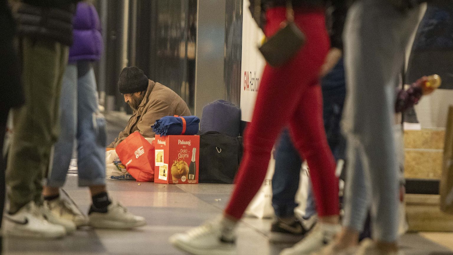 Un clochard dorme in strada, nel centro di Milano