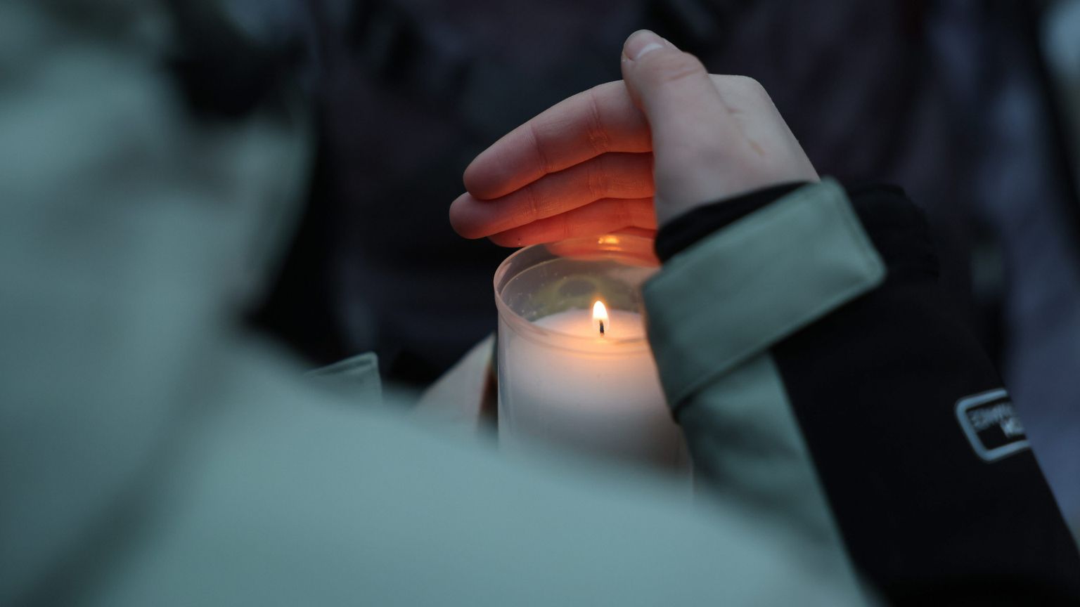 Una candela tra le mani di una ragazza nel luogo del “memoriale” improvvisato a Crans-Montana davanti al locale della tragedia