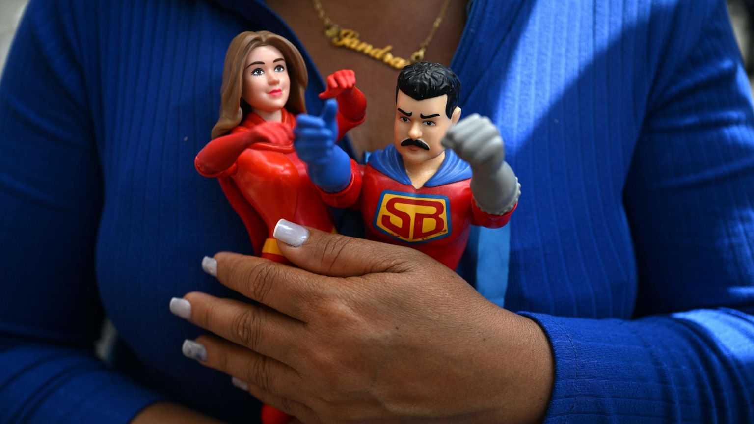 Una donna di Caracas stringe tra le mani le statuine di Nicolas Maduro e della moglie Cilia Flores, catturati e portati via dal Paese