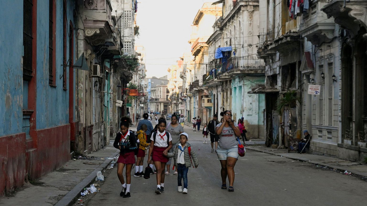 Un gruppo di bambini in uniforme scolastico cammina per il centro dell'Avana fra edifici malridotti per la mancanza di manutenzione
