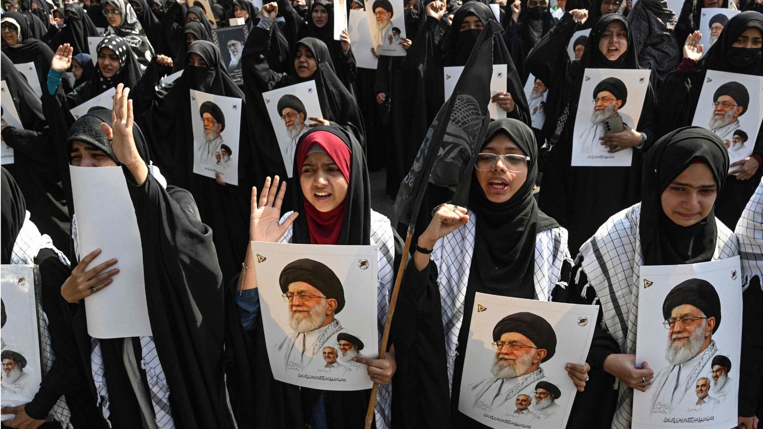 Una folla di donne con il lungo abito nero e la testa velata tengono in mano fotografie di Khamenei in segno di protesta