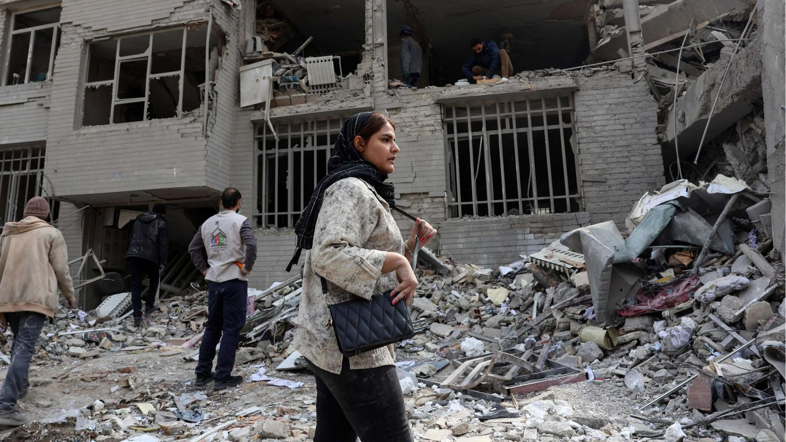 Una donna davanti a un edificio distrutto a Teheran