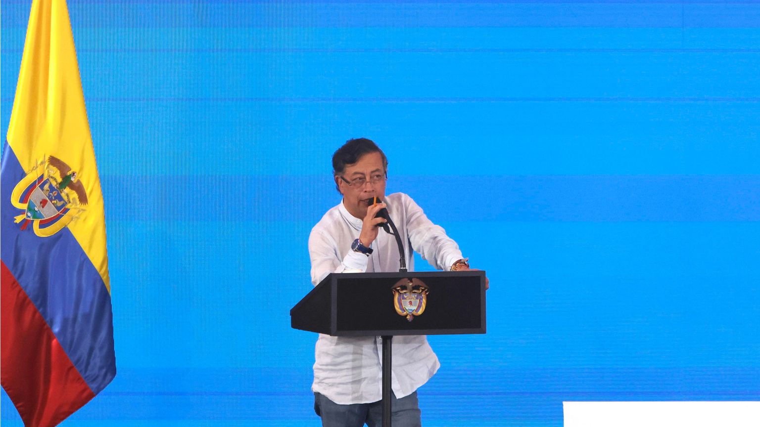 Il presidente Gustavo Petro parla sul palco della Conferenza di Santa Marta accanto alla bandiera colombiana