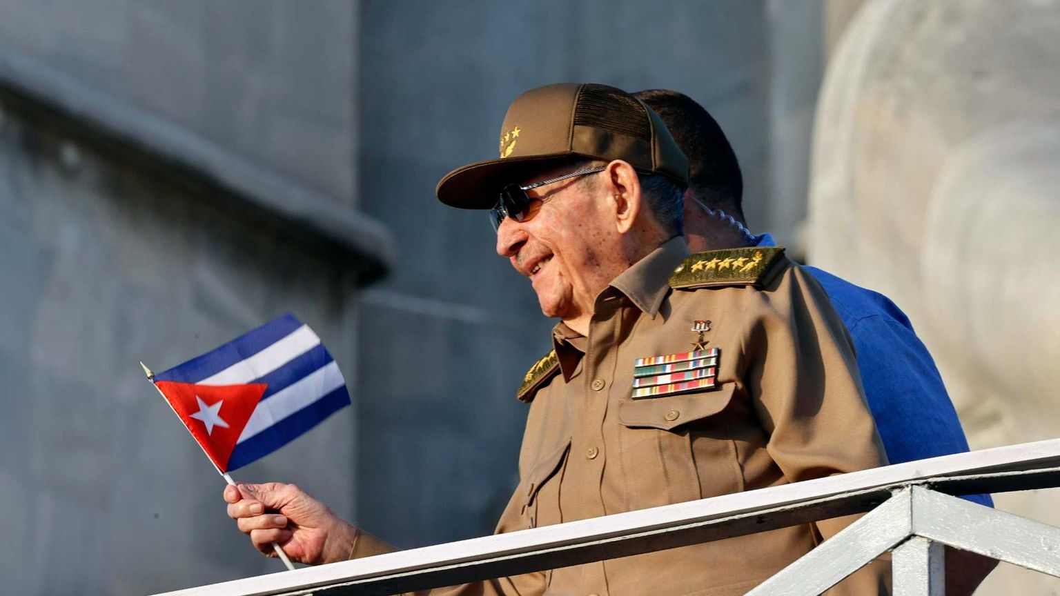 Un uomo si sporge da un parapetto con una bandiera cubana in mano. Si tratta di Raul Castro, ex presidente cubano