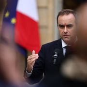Sebastien Lecornu davanti a un microfono, con un'espressione tesa, la fronte corrugata. Alle sue spalle le bandiere francese e dell'Ue