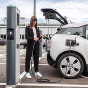 Una ragazza ricarica la propria auto elettrica da una colonnina pubblica