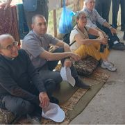 Nella fotto si vedono l’arcivescovo di Milano Mario Delpini seduto a terra in un villaggio beduino con altri partecipanti al recente pellegrinaggio in Terra Santa