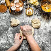 Mani che impastano su un tavolo con farina, uova