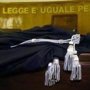 L'immagine ritrae una toga da magistrato sul banco di un Tribunale italiano, sullo sfondo la scritta "La legge è uguale per tutti"
