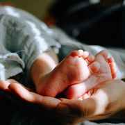 Una mamma tiene tra le mani i piedi del suo bambino. Foto d'archivio