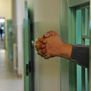 Due mani che sporgono dalle sbarre di un carcere