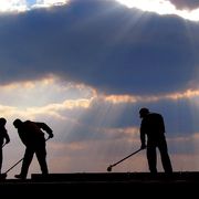 L'immagine mostra tre uomini che stanno lavorando su un ponteggio alla luce di un tramonto