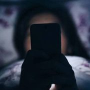 Una ragazzina davanti al suo smartphone in cameretta