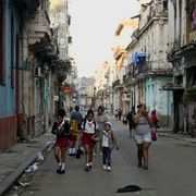 Un gruppo di bambini in uniforme scolastico cammina per il centro dell'Avana fra edifici malridotti per la mancanza di manutenzione