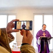 Un sacerdote ripreso con uno smartphone