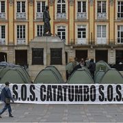 Due persone passano davanti a una serie di tende nella piazza Bolívar di Bogotà e alla scritta: "S.O.S. Catatumbo". Con l'iniziativa, i promotori hanno voluto denunciare la violenza nella regione ocolombiana