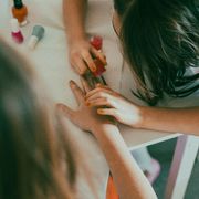 Una bimba gioca a fare lo smalto a una sua amichetta