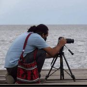 Carlos Choc è inginocchiato sulle sponde di un lago per scattare una fotografia con la sua macchina