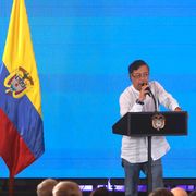 Il presidente Gustavo Petro parla sul palco della Conferenza di Santa Marta accanto alla bandiera colombiana