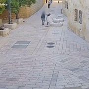 Una vasta via piastrellata, con pochissime persone: un uomo aggredisce alle spalle una suora in abito bianco e velo nero