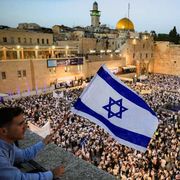 Un giovane nazionalista agita una bandiera israeliana da un balcone davanti alla folla radunata al Muro Occidentale di Gerusalemme