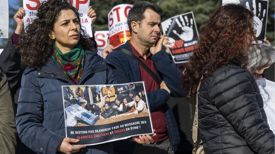 Una donna con un cartello che recita: "Non restiamo in silenzio davanti al massacro di alauiti, cristiani e drusi in Siria"