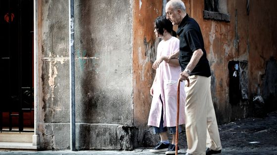Una badante accompagna un anziano signore per le vie di Roma