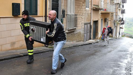 Volontari della Protezione civile e comuni cittadini aiutano le persone a svuotare le proprie case in bilico sull'abisso, a Niscemi / ANSA