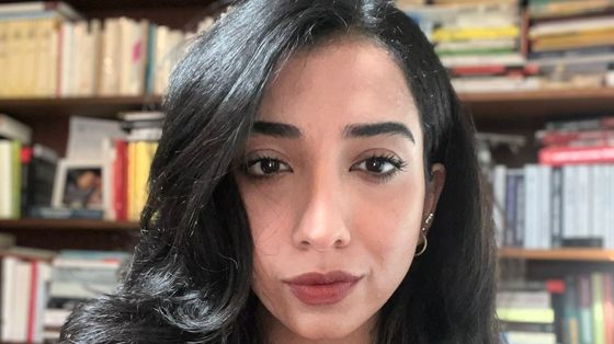 Il volto in primo piano di una giovane ragazza dagli occhi neri e i capelli neri lunghi e sciolti