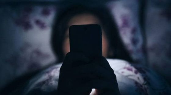 Una ragazzina davanti al suo smartphone in cameretta