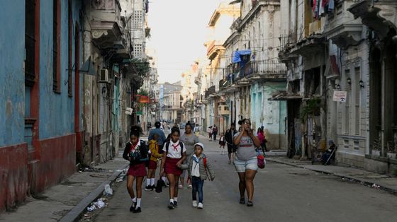 Un gruppo di bambini in uniforme scolastico cammina per il centro dell'Avana fra edifici malridotti per la mancanza di manutenzione