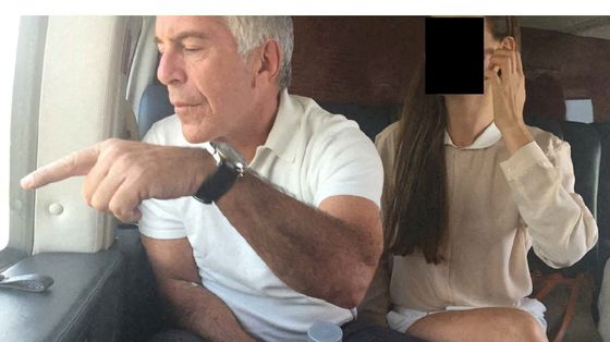 Il finanziere Jeffrey Epstein a bordo di un aereo indica qualcosa dal finestro. Al suo financo una donna il cui volto è stato oscurato per ragioni di riservatezza