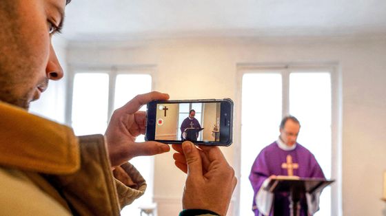 Un sacerdote ripreso con uno smartphone