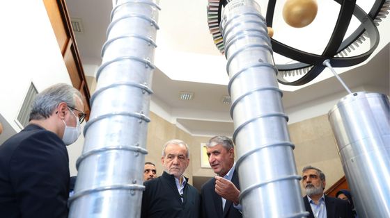 Un gruppo di funzionari iraniani e il presidente Massud Pezeshkian ispezionano dei grandi cilindri grigi in uno degli impianti del programma nucleare