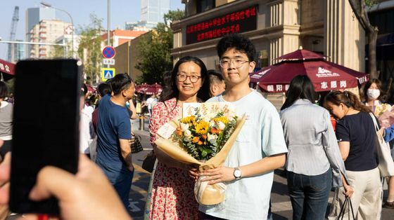Studenti delle scuole superiori e le loro famiglie posano per le foto dopo aver sostenuto il Gaokao a Pechino nel 2025