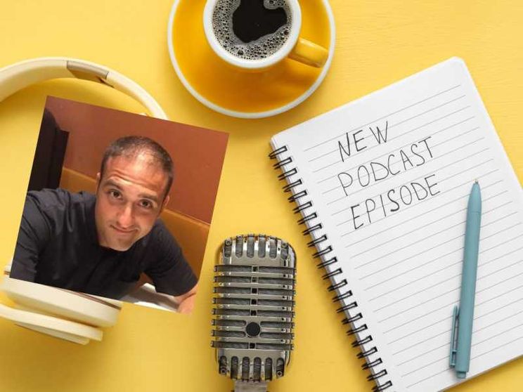 Cuffie, microfono e un quaderno sono pronti per la registrazione di un nuovo episodio di un podcast, accompagnati da una tazza di caffè