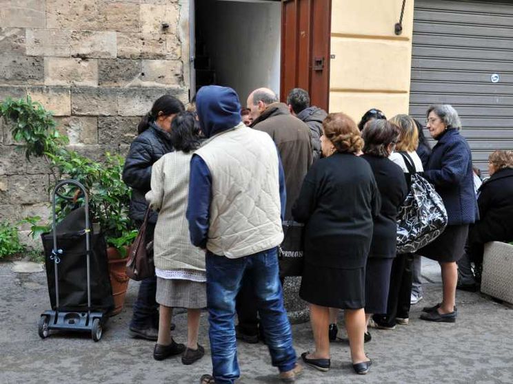 Famiglie povere mangiano a una mensa della Caritas