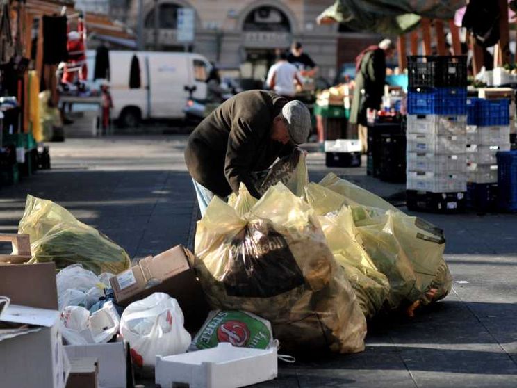 Un anziano fruga tra i rifiuti del mercato di piazza S. Cosimato a Trastevere, a Roma per cercare del cibo da mangiare