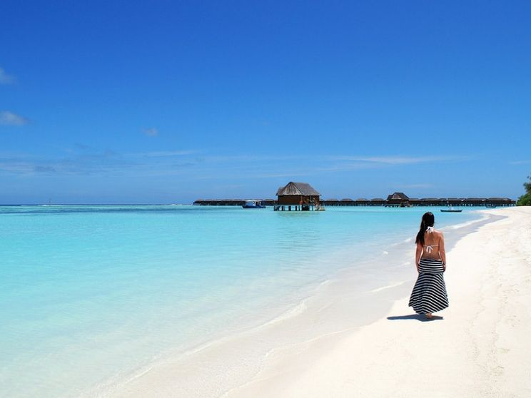 Una giovane cammina su una spiaggia delle Maldive