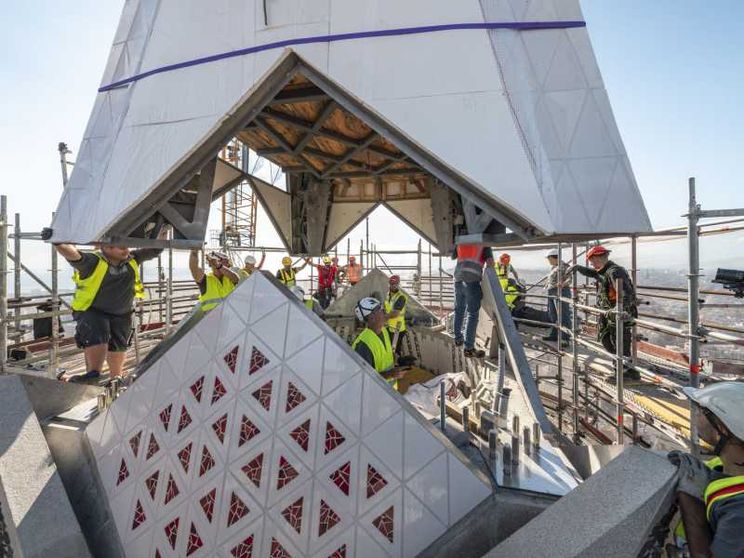 Il braccio inferiore della croce collocato sulla Torre di Gesù Cristo con operai a lavoro