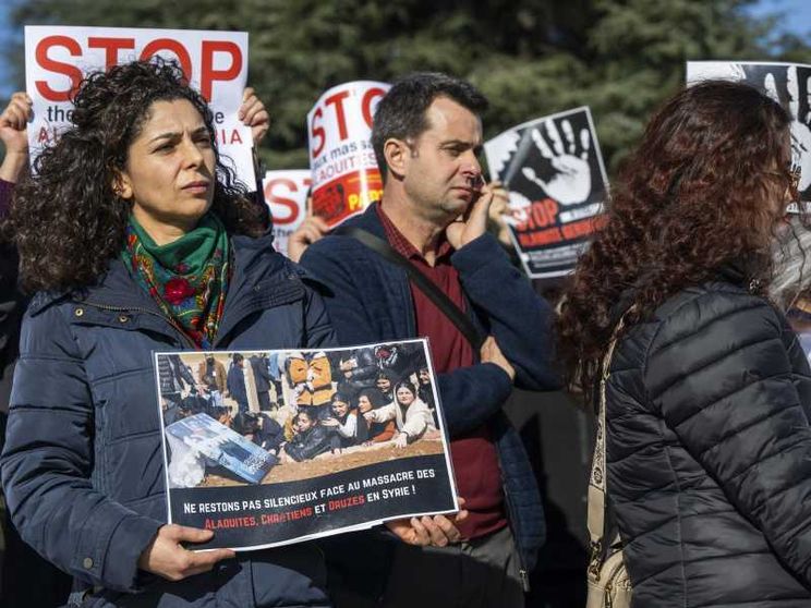 Una donna con un cartello che recita: "Non restiamo in silenzio davanti al massacro di alauiti, cristiani e drusi in Siria"