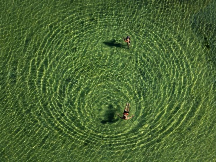 Due bagnanti in un lago del Trentino fra acque cristalline. Un'immagine sorprendente scattata da Massimo Sestini dall'elicottero