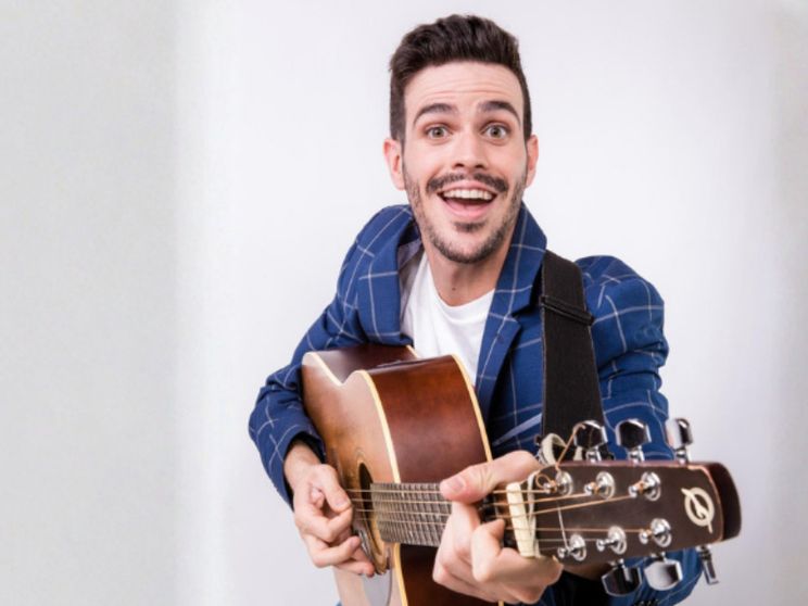 Lorenzo Baglioni, attore, ex-docente, conduttore televisivo, tiene in mano una radio rossa e nera, e sorride