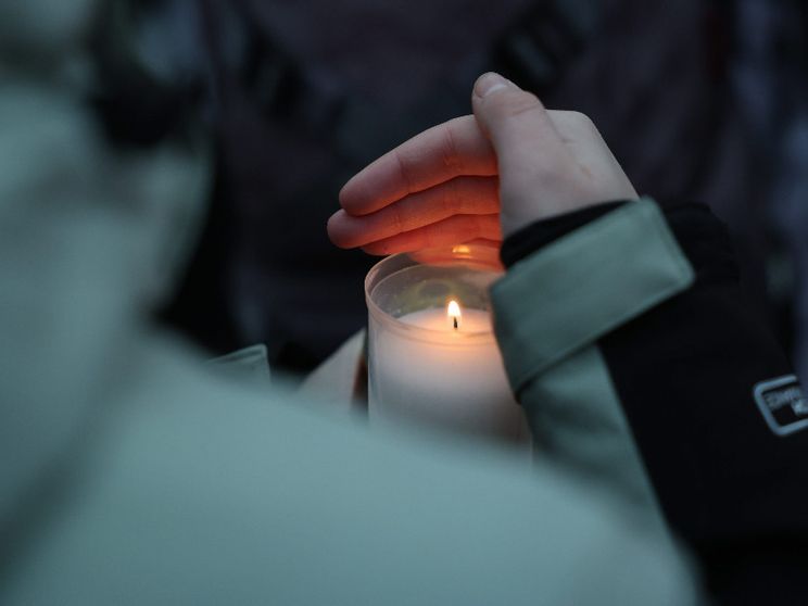 Una candela tra le mani di una ragazza nel luogo del “memoriale” improvvisato a Crans-Montana davanti al locale della tragedia