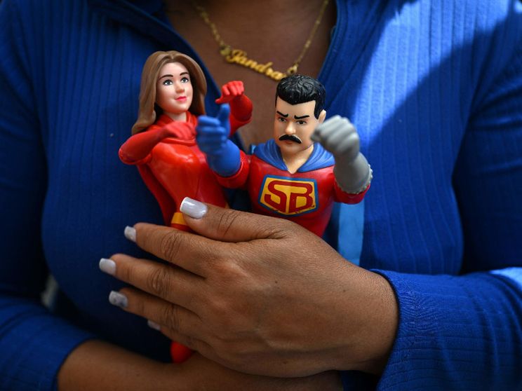 Una donna di Caracas stringe tra le mani le statuine di Nicolas Maduro e della moglie Cilia Flores, catturati e portati via dal Paese