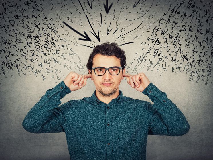 Un uomo si tappa le orecchie mentre tutto intorno volano parole