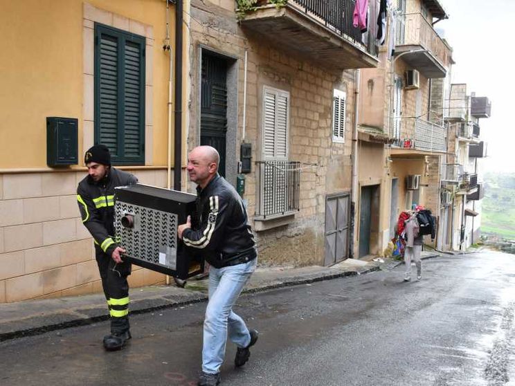 Volontari della Protezione civile e comuni cittadini aiutano le persone a svuotare le proprie case in bilico sull'abisso, a Niscemi / ANSA