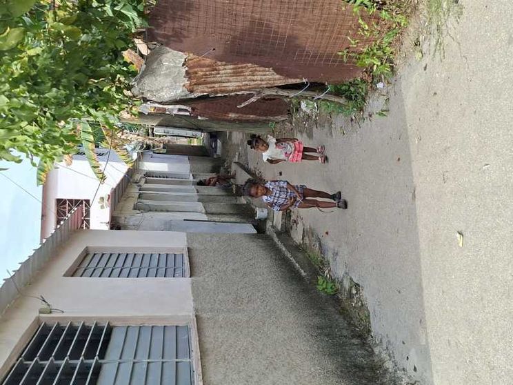 Due bambini cammino in un viottolo sterrato di una baraccopoli dell'Avana su cui si affacciano casupole di compensato e lamiera