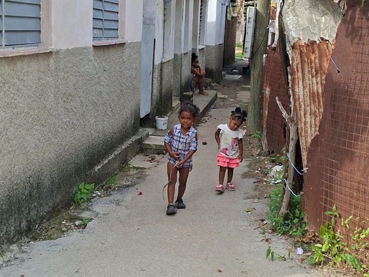 Due bambini cammino in un viottolo sterrato di una baraccopoli dell'Avana su cui si affacciano casupole di compensato e lamiera